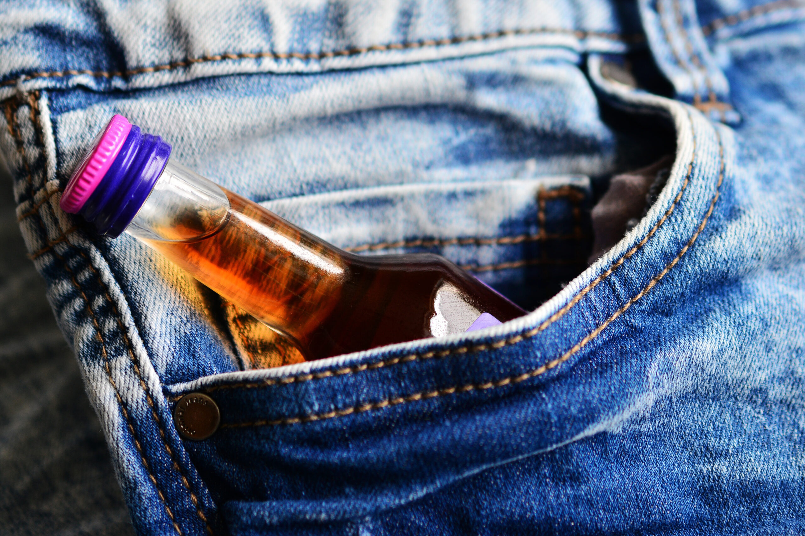 a bottle of alcohol in a jeans pocket